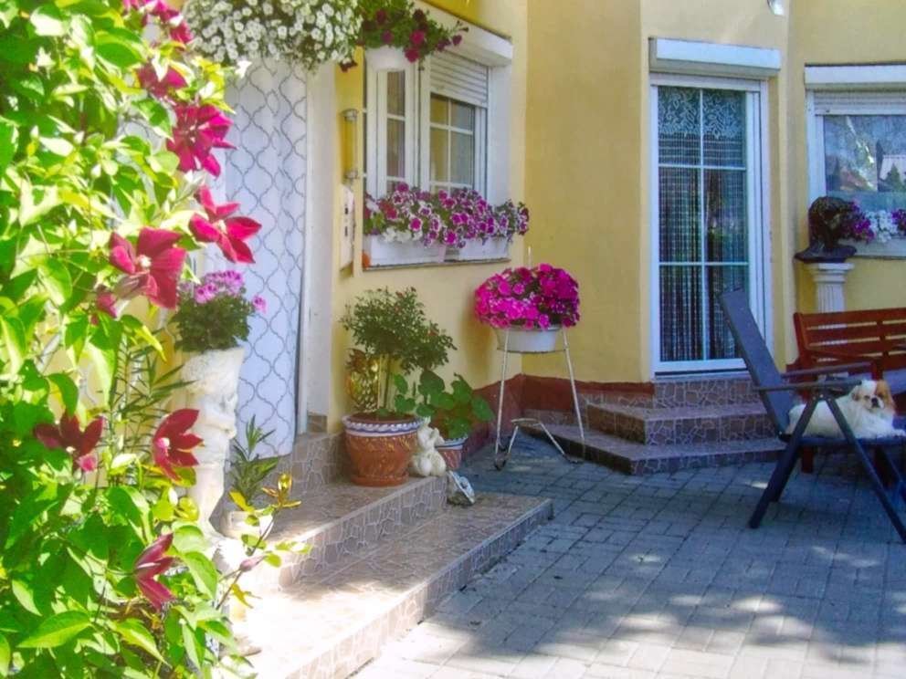 Einladender Eingangsbereich mit Charme: Hochwertige Naturstein-Terrasse mit Blumenoase und stufenlosem Zugang