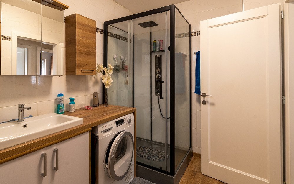 Modernes Badezimmer mit begehbarer Duschkabine und praktischer Wäscheintegration Modernes Badezimmer mit begehbarer Duschkabine und praktischer Wäscheintegration